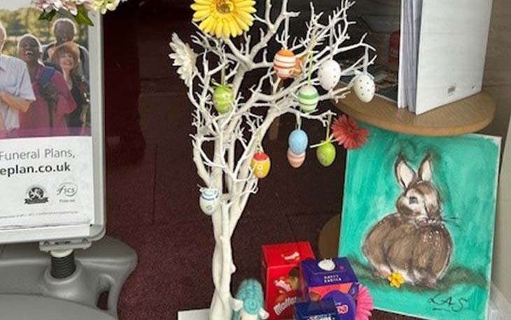 A display window with a tree with eggs, flowers and a hand painted picture of a bunny.