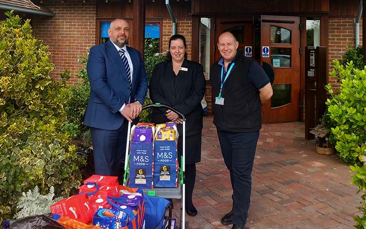 3 people standing in front of wooden door with bags full of Easter egg donations.